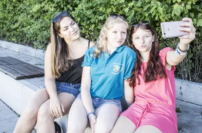 drei junge Mitglieder schauen in ein Handy und machen ein Selfie