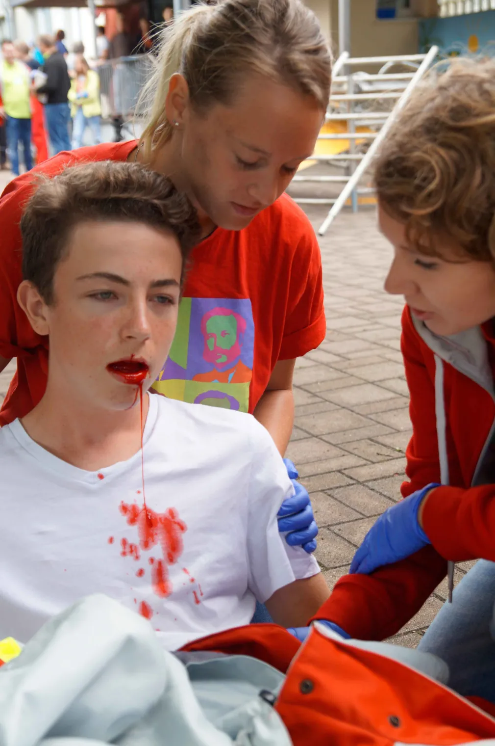Ein Jugendlicher blutet aus dem Mund. Zwei JRKlerinnen versorgen den Verletzten.