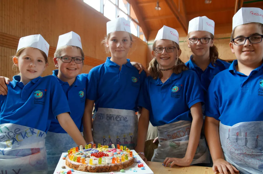 Sechs Kinder stehen vor einem selbst verzierten Kuchen