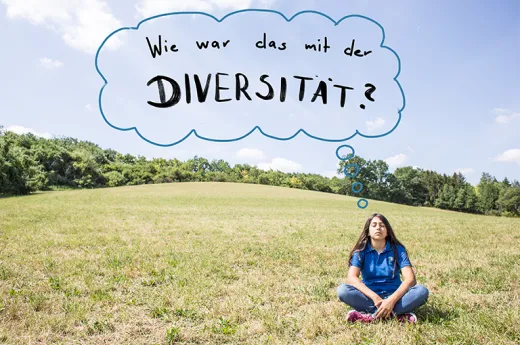 Ein Mädchen sitzt im Schneidersitz auf einer großen Wiese. Über Ihr ist eine Denkblase zu sehen mit dem Inhalt "Wie war das mit der Diversität?""