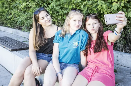 Social Media Nutzung JRK drei junge Mitglieder schauen in ein Handy und machen ein Selfie