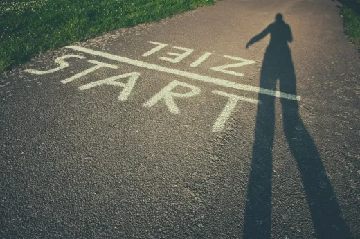 © suze / photocase.de Eine laufende Person auf der Straße auf der die Worte Start und Ziel stehen