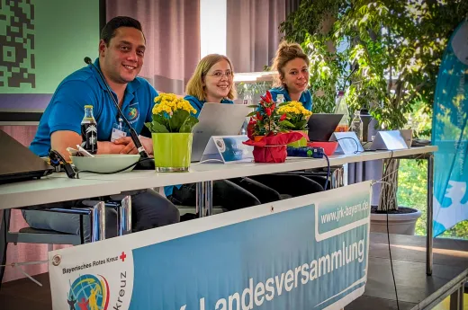 Die Landesleitung sitzend auf der Bühne bei der JRK-Landesversammlung 2023 Die Landesleitung sitzend auf der Bühne bei der JRK-Landesversammlung 2023