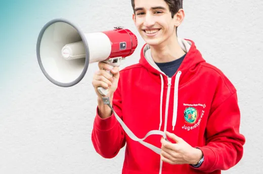 Ein Jugendrotkreuzler hält ein Megaphone in der Hand
