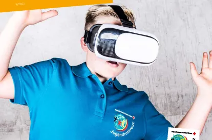 Das Bild zeigt das Cover der baff-Ausgabe 3-2022 zum Tiotelthema Zuunft. Darauf ist ein Junge im Jugendrotkreuz T-Shirt zu sehen, der eine VR-Brille trägt.